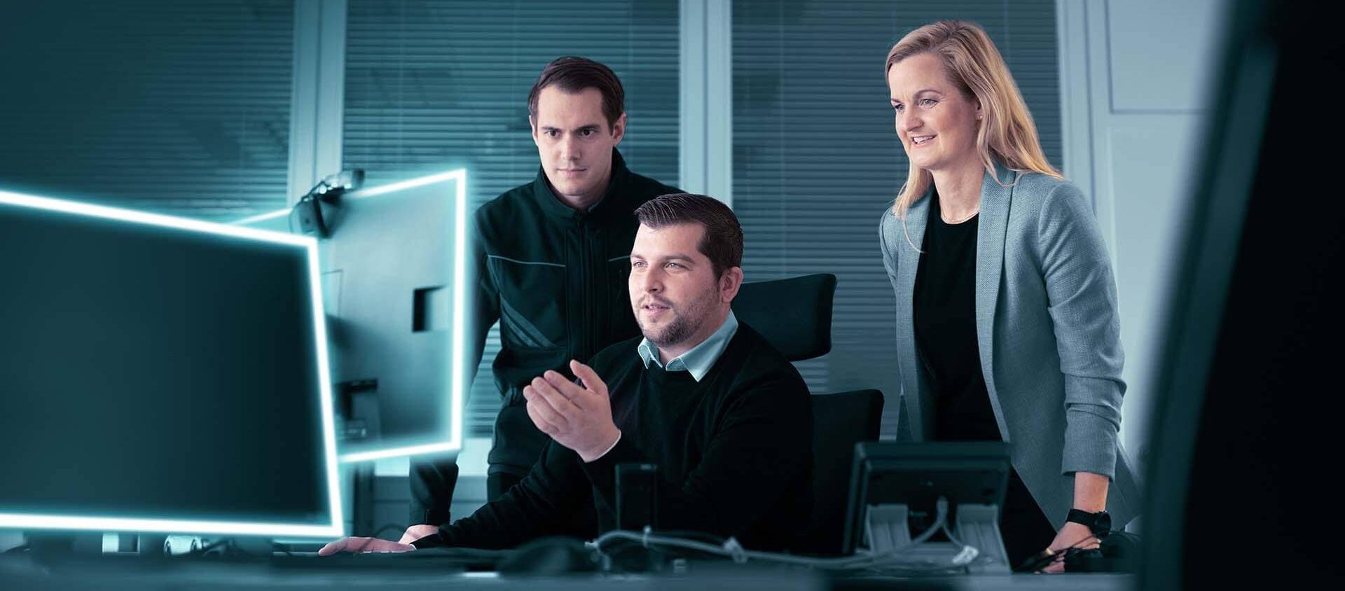 drei Mitarbeiter versammelt vor einem Rechner
