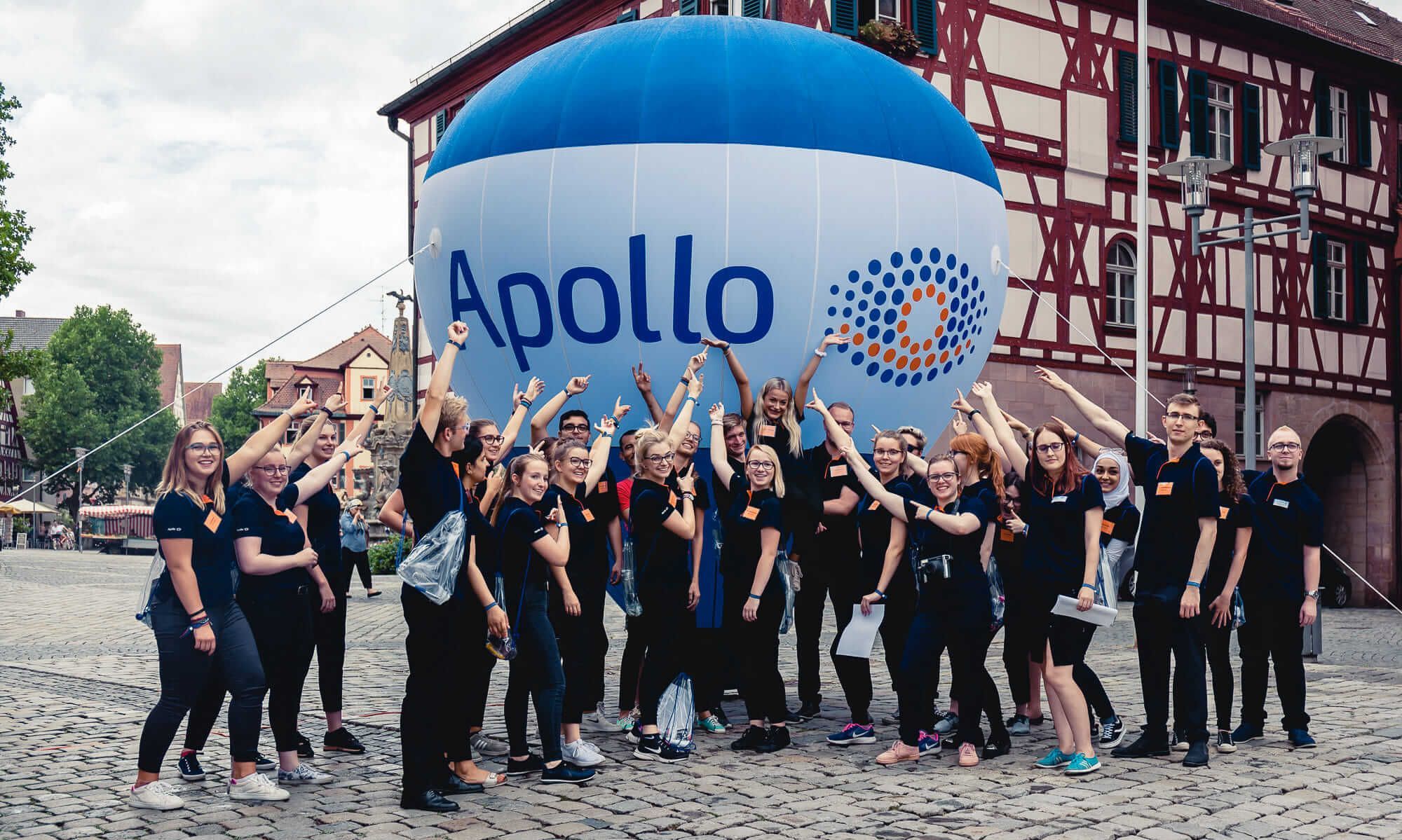 Gruppenfoto von Mitarbeitern vor Apollo-Schriftzug