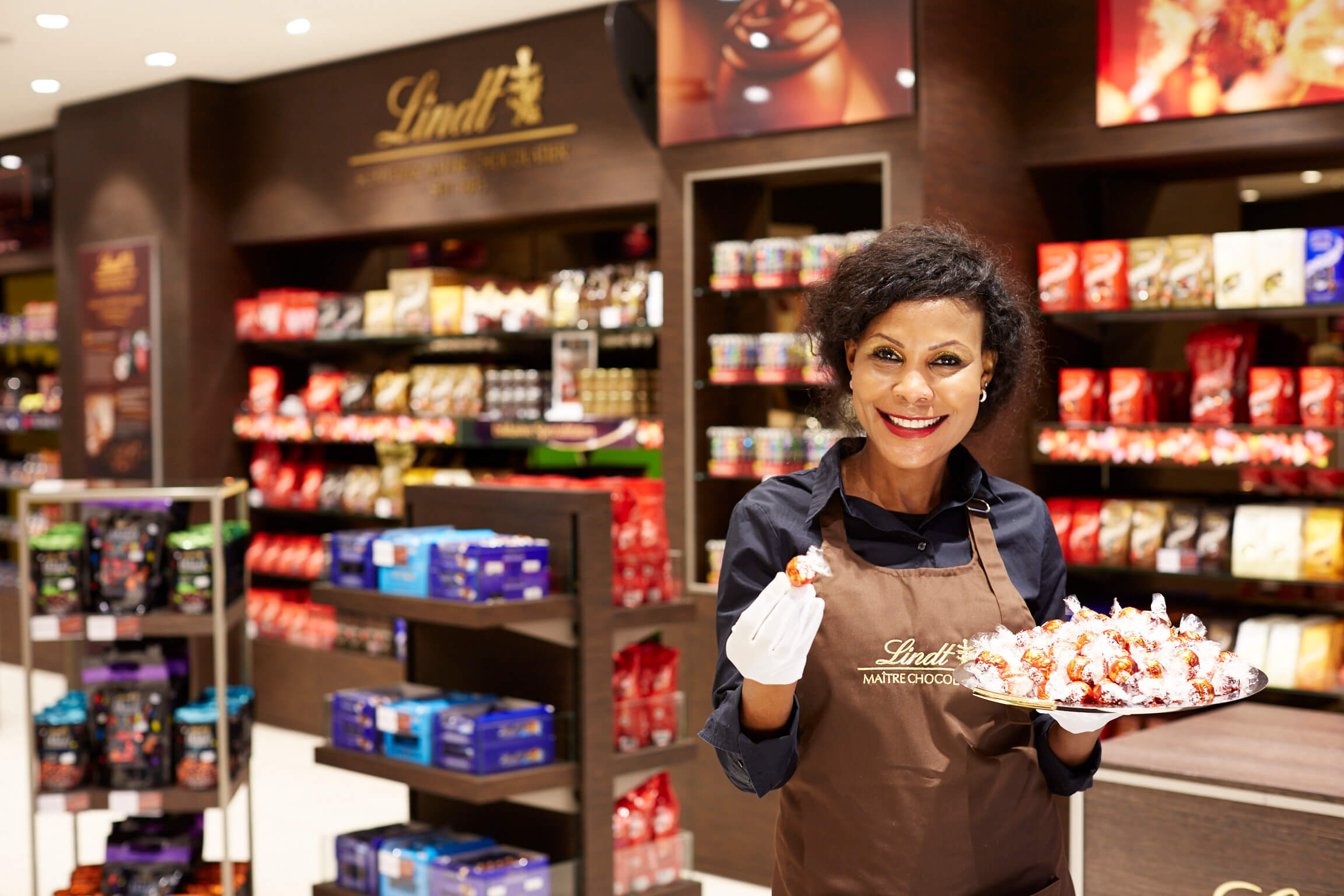 Verkäuferin in Lindt-Geschäft, bietet Schokolade an