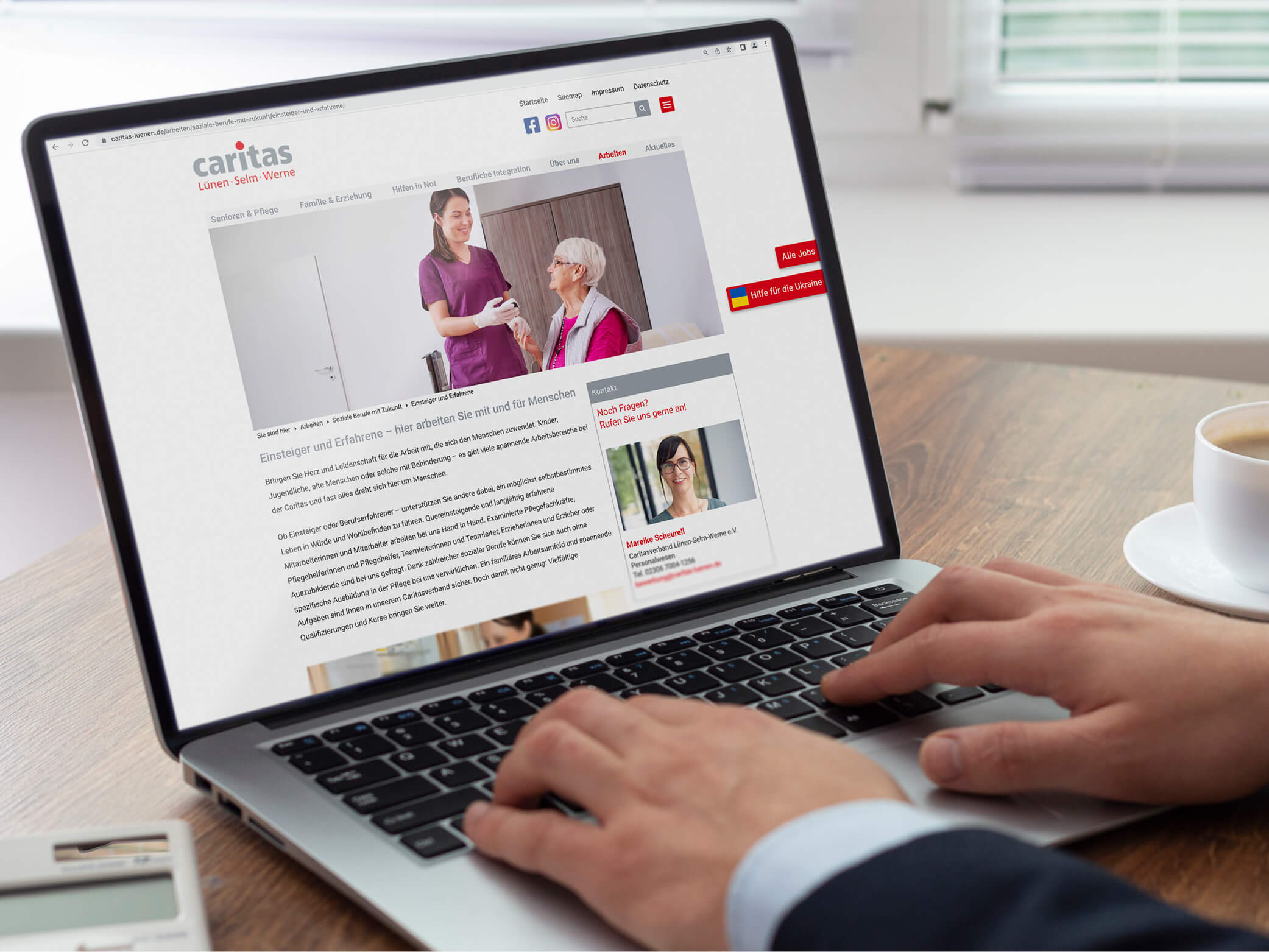 Karrierewebsite der caritas Lünen-Selm-Werne auf Laptop-Bildschirm, Hände tippen darauf