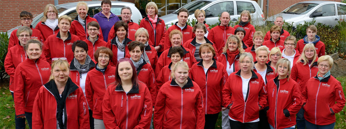 Teamfoto der ambulanten Pflege, alle in roter Caritas-Kleidung